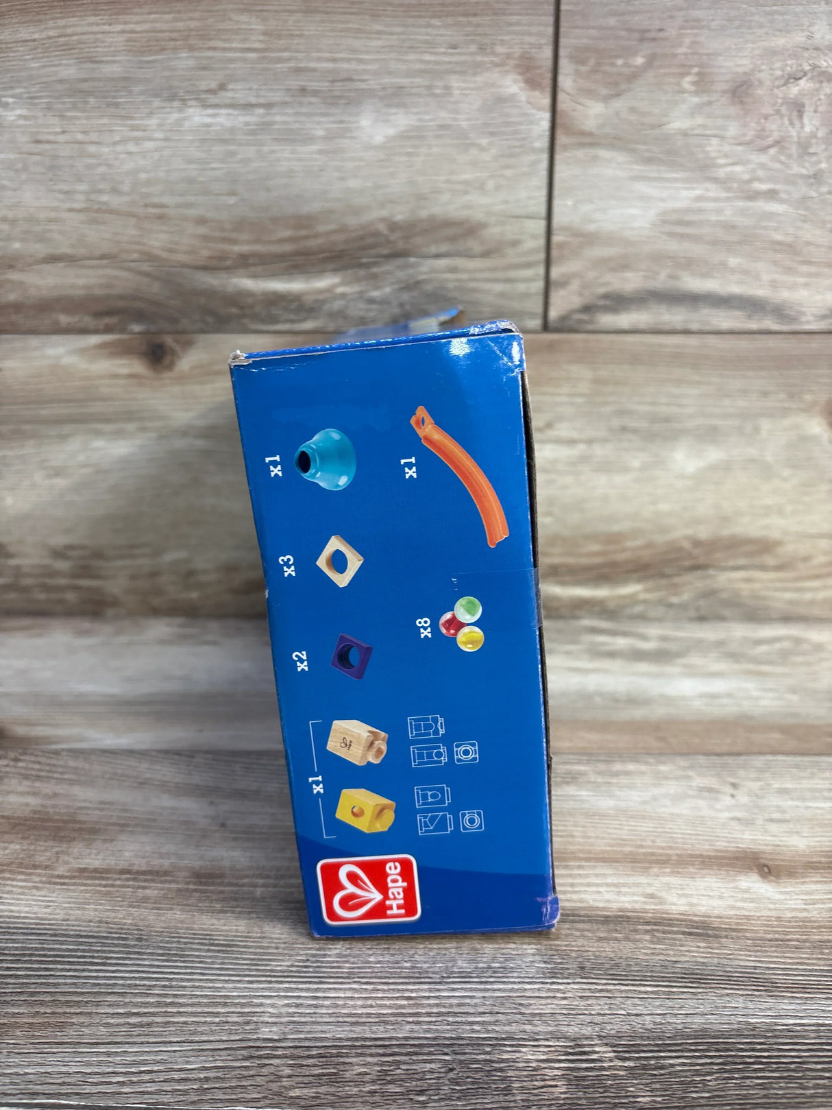 Side view of Hape Quadrilla Mega Skatepark playset box showing included wooden track pieces, connector blocks, and marbles