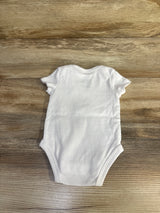 Back view of white Nike baby bodysuit, 3 months, showing short sleeves and leg openings, laid flat on wood background