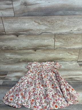 Flat lay of girls' ivory floral swing dress size 5T showing short ruffle sleeves and tiered skirt on light wood background