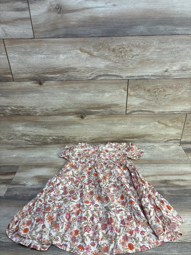 Flat lay of girls' ivory floral swing dress size 5T showing short ruffle sleeves and tiered skirt on light wood background
