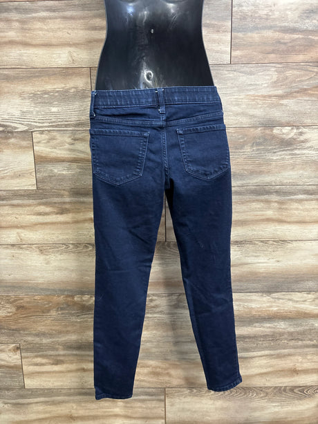 Back view of blue maternity jeggings showing side-panel waistband, back pockets, and tapered legs against wood plank background
