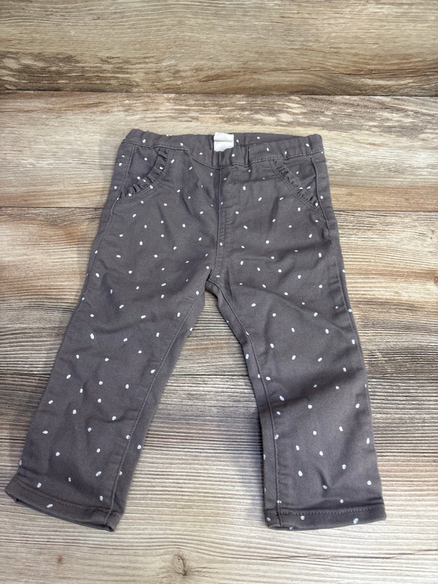 Children's gray pants with white polka dots laid flat on wooden surface, kids clothing