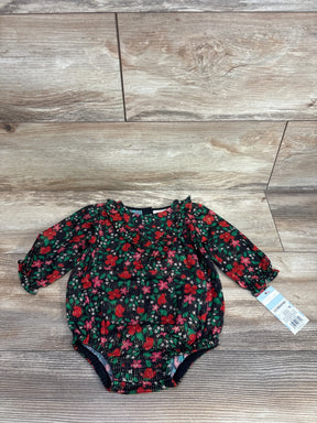Long sleeve baby romper with red floral print and ruffled neckline on wood background