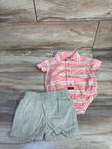 Flat lay of Wrangler pink striped polo bodysuit with khaki shorts, showing front buttons and snaps on wood background