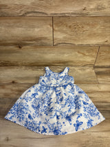 Flat lay of white sleeveless toddler dress 18 month showcasing blue floral and bird print and gathered skirt with wood floor background