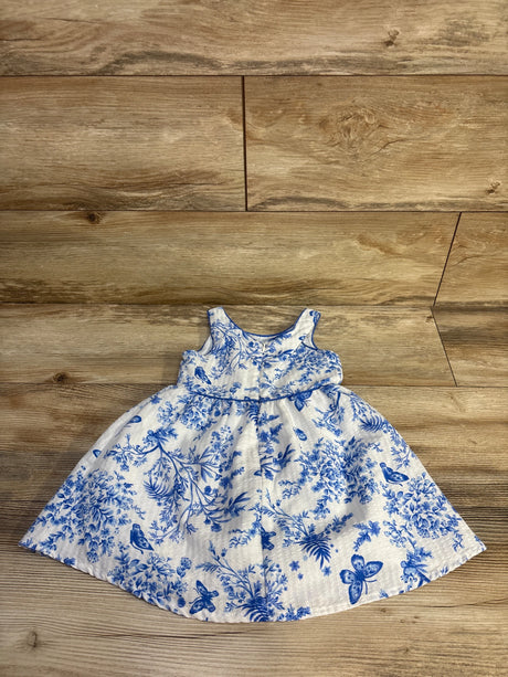 Flat lay of white sleeveless toddler dress 18 month showcasing blue floral and bird print and gathered skirt with wood floor background