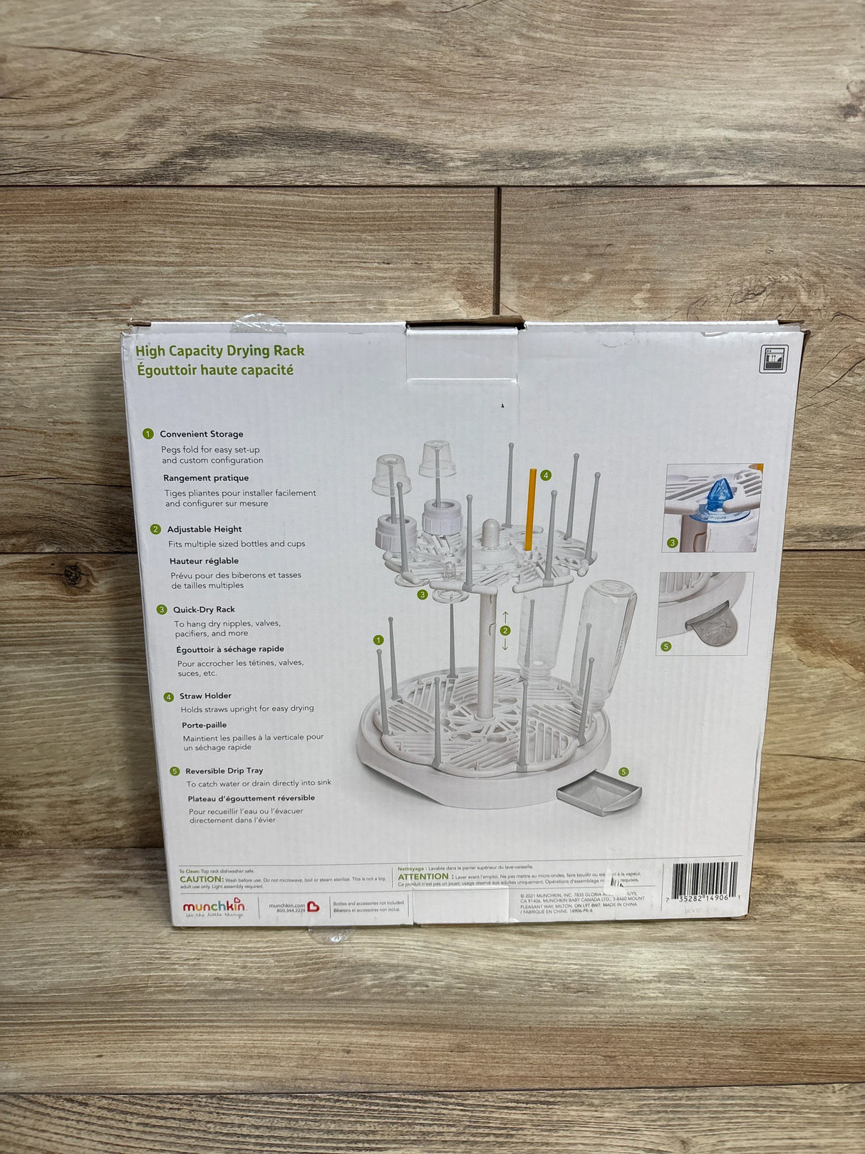 Front view of Munchkin High Capacity Bottle Drying Rack showing two-tier rack with adjustable pegs and removable drip tray on wood floor