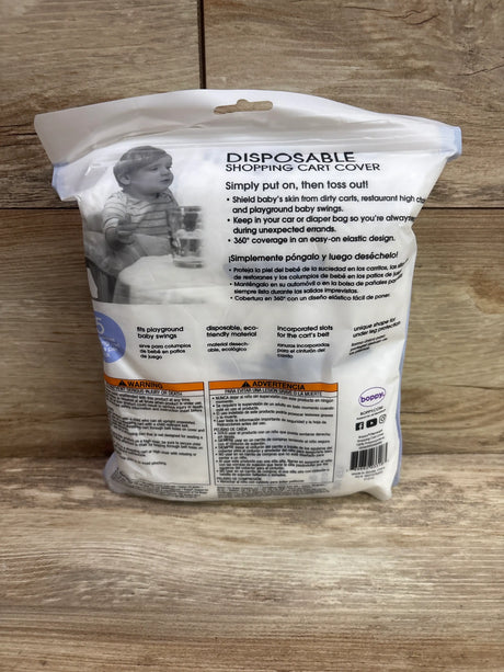 Back of Boppy disposable shopping cart cover package showing 360 degree coverage and easy on elastic design on a wood surface