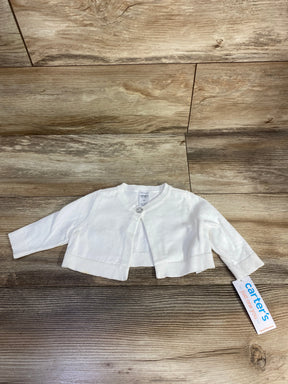 White long-sleeve baby cardigan with a single button and carter's clothing tag on wood floor