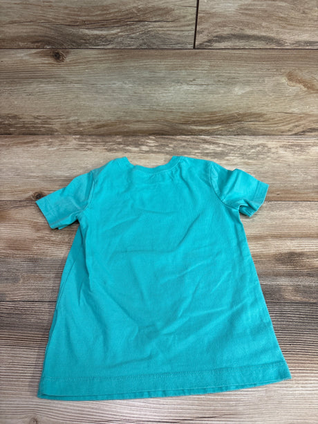 Back view of a teal Carter's dinosaur shirt for toddlers size 3T on a wooden background.