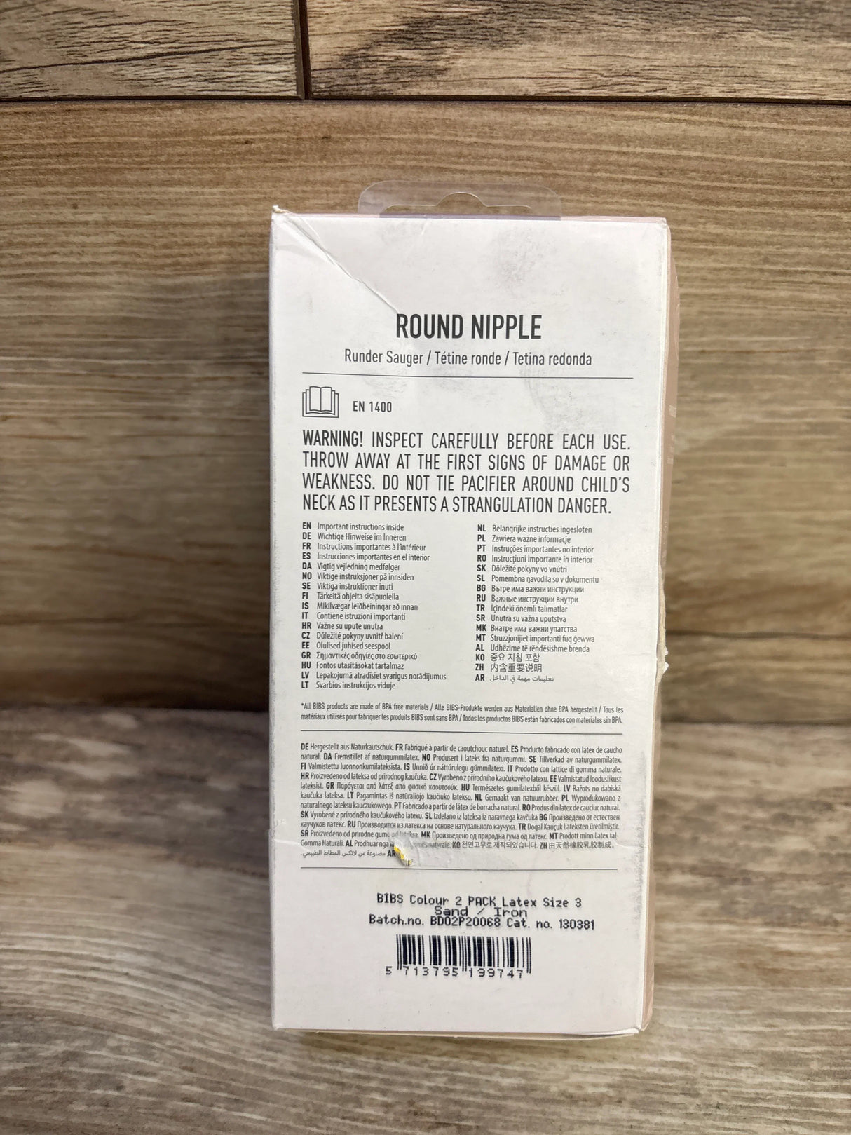 Back view of BIBS Colour size 3 natural rubber pacifier 2-pack showcasing warning text, Round Nipple label and barcode on wood surface background