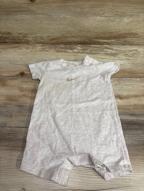 Beige Nike shortie romper for baby size 0-6m laid flat on a wood floor.