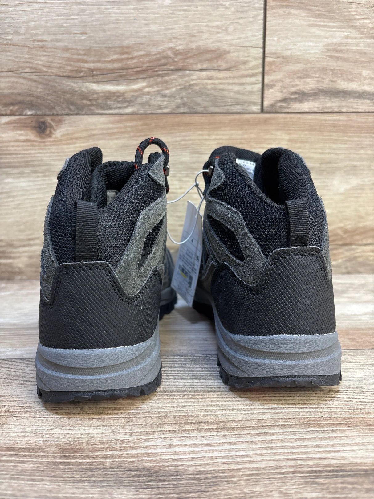 Rear view of kids' black and gray athletic sneakers on wood floor, resale condition