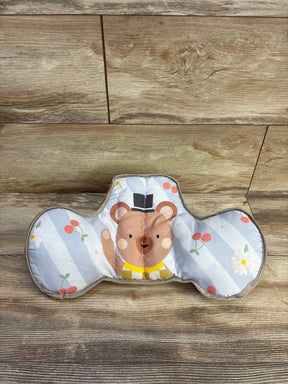 Front view of Taf Toys tummy time support pillow showing printed bear face and two side bolsters on wood floor background