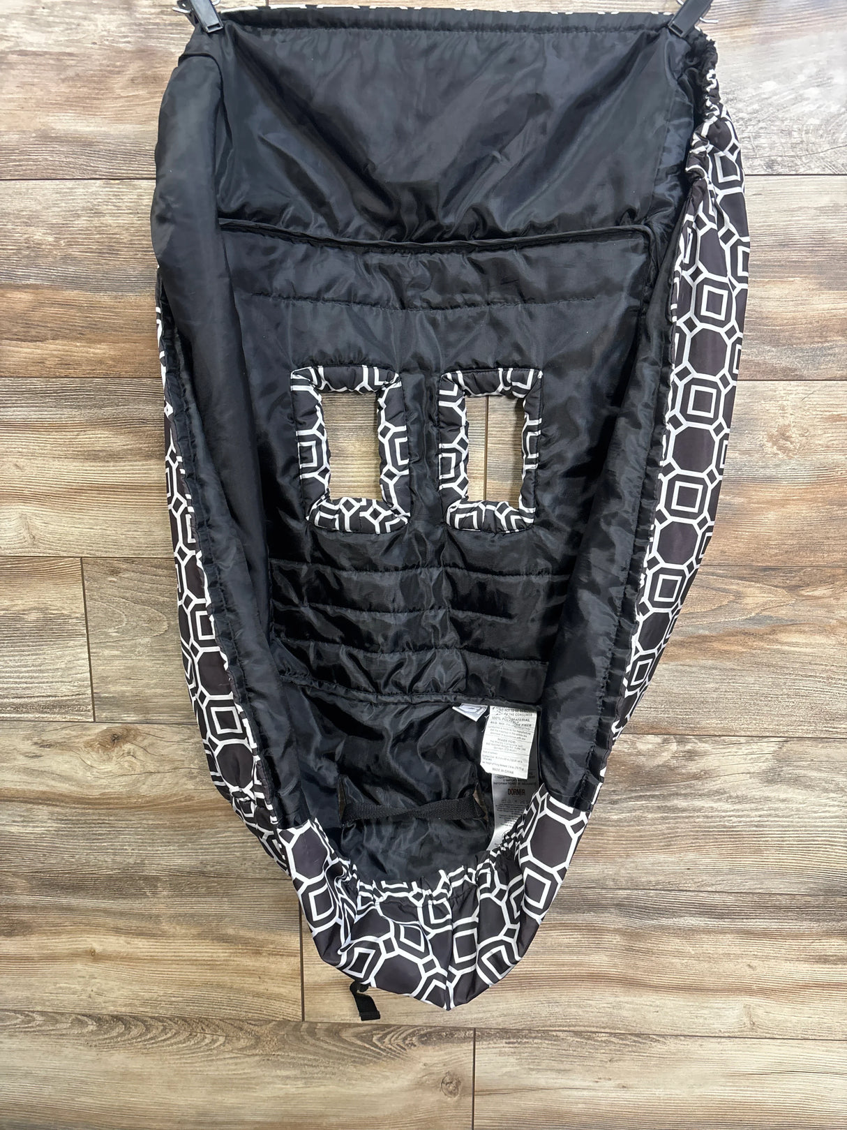 Top-down of Boppy cart and high chair cover: black quilted interior, two rectangular harness openings, geometric edge