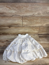 White ruffled baby dress with sleeveless bodice displayed on wood background