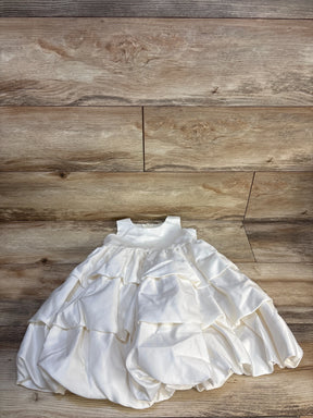 White ruffled baby dress with sleeveless bodice displayed on wood background
