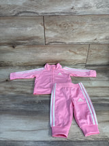 Flat lay of pink Adidas baby tracksuit (3M) showcasing white three-stripe trim and Adidas logos on wood background