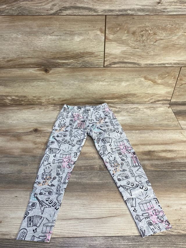 Flat lay of grey Spotted Zebra Rock leggings showing all-over music and instrument doodle print with pink and teal accents on wood background