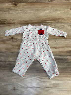 Grey baby romper with red heart pattern and ladybug patch, long sleeves, wooden floor background