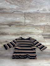 Striped long-sleeve toddler shirt in black, brown, white, and orange on wood floor background