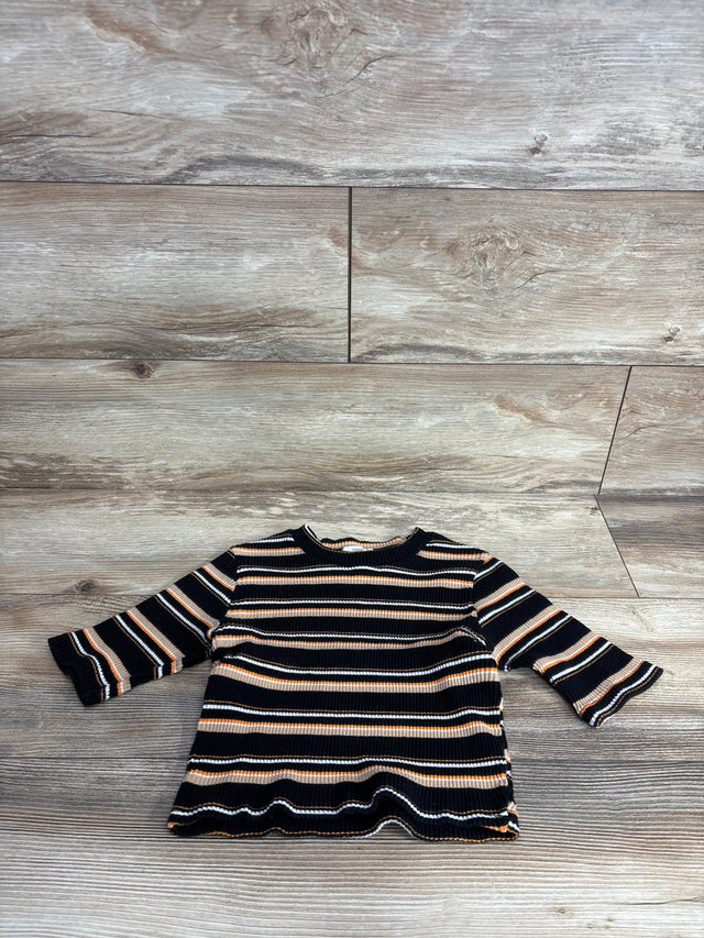 Striped long-sleeve toddler shirt in black, brown, white, and orange on wood floor background