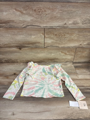 Flat lay of NEW Grayson Mini Tie-Dye Ruffle Top in pastel pink green and yellow swirl with shoulder ruffles and hangtag on wood plank floor
