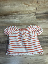 Flat lay of toddler white shirt with orange horizontal stripes and puff sleeves, elastic gathered neckline on wood floor