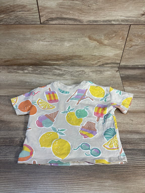 Top view of cream baby short-sleeve shirt with pastel fruit and ice cream motifs on wood background