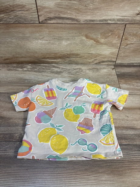 Top view of cream baby short-sleeve shirt with pastel fruit and ice cream motifs on wood background