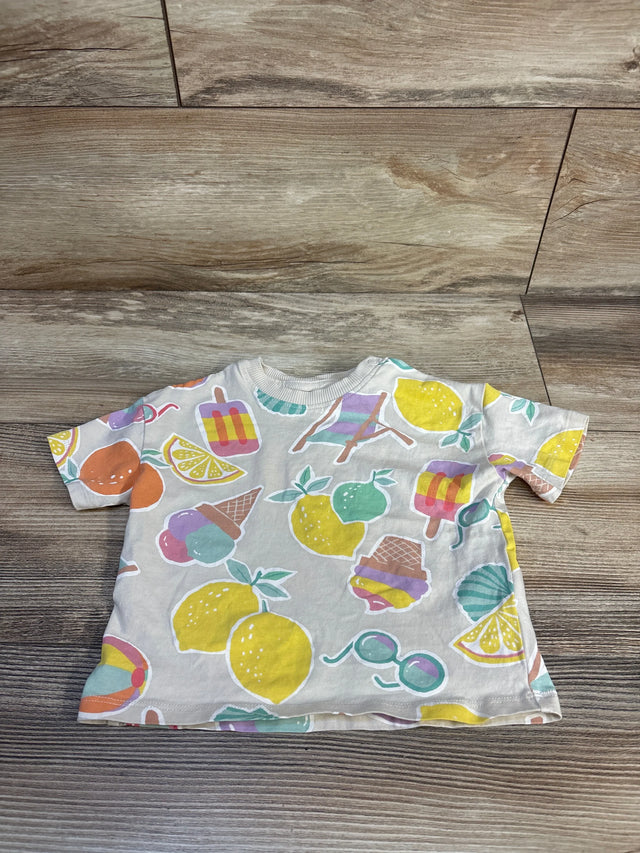 Top view of cream baby short-sleeve shirt with pastel fruit and ice cream motifs on wood background