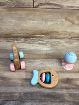 Wooden baby toys including fish rattle, pastel roller, and blue jellyfish on wood floor