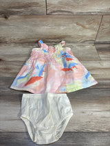 Flat lay of pink multicolor baby dress showing smocked ruffle bodice with matching white bloomers on wooden floor