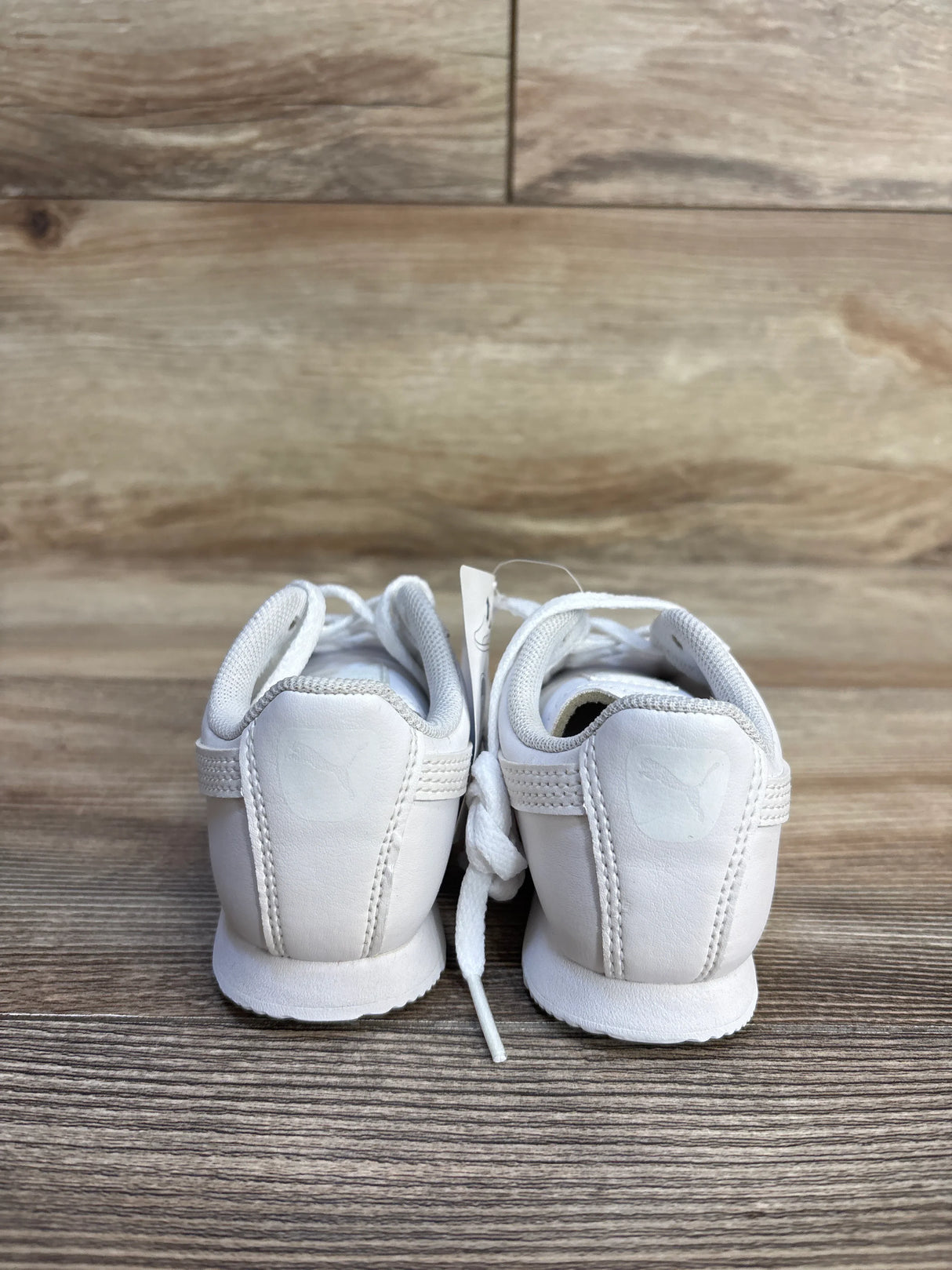 Back view of white toddler athletic sneakers on wood surface