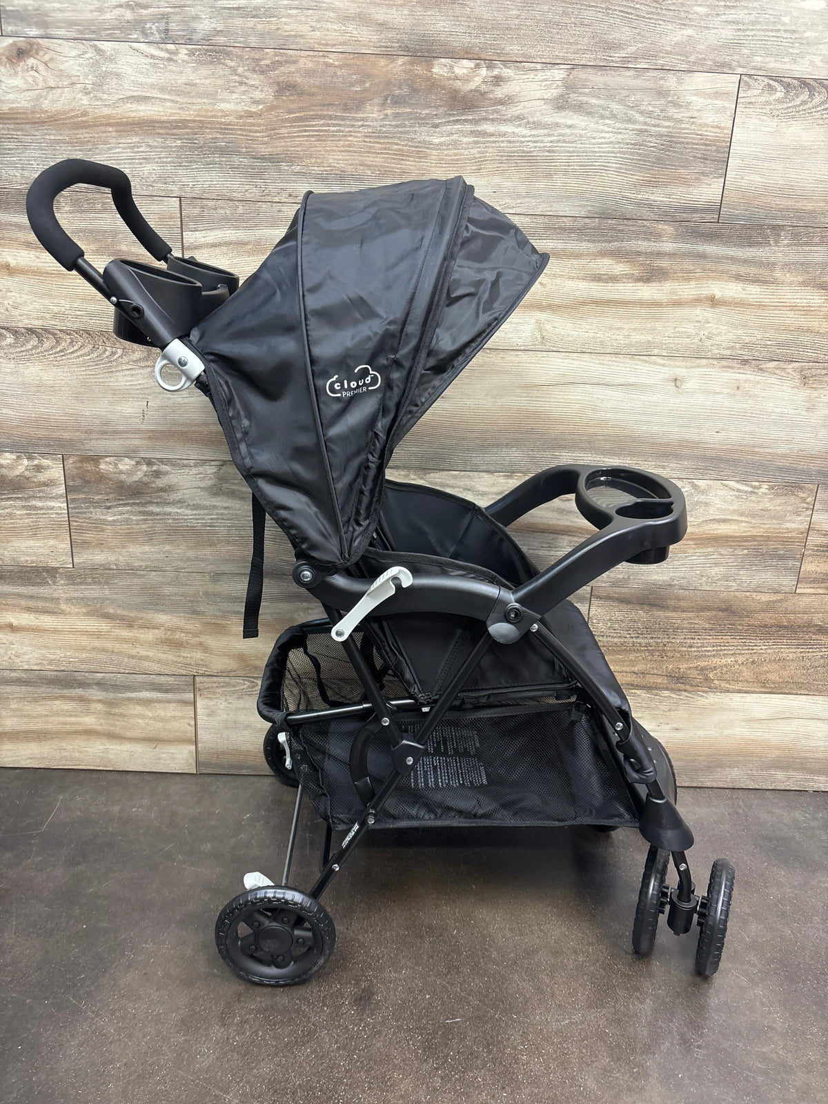 Front view of Kolcraft Cloud Premier stroller in black showing canopy, cup holder, and storage basket