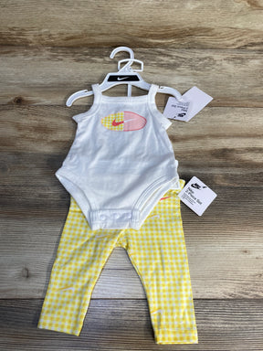 Nike baby outfit with white bodysuit and yellow checkered leggings on wooden background