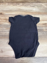 Back view of black NFL Team Apparel Raiders bodysuit with short sleeves on a wood-grain background