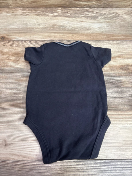 Back view of black NFL Team Apparel Raiders bodysuit with short sleeves on a wood-grain background