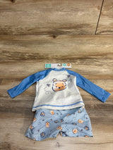 Flat lay of Disney Baby Winnie the Pooh rash guard set showing blue long-sleeve UPF 50+ top and striped shorts on wood floor, size 9M