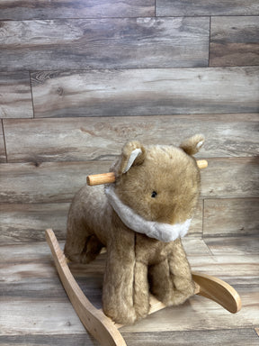 Plush bear rocking horse toy with wooden curved rockers and handle against wood planked background