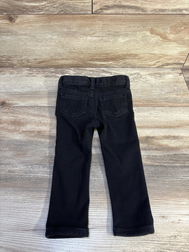 Back view of black Cat & Jack toddler jeggings, size 18 months, showing back pockets and straight legs on a light wood background