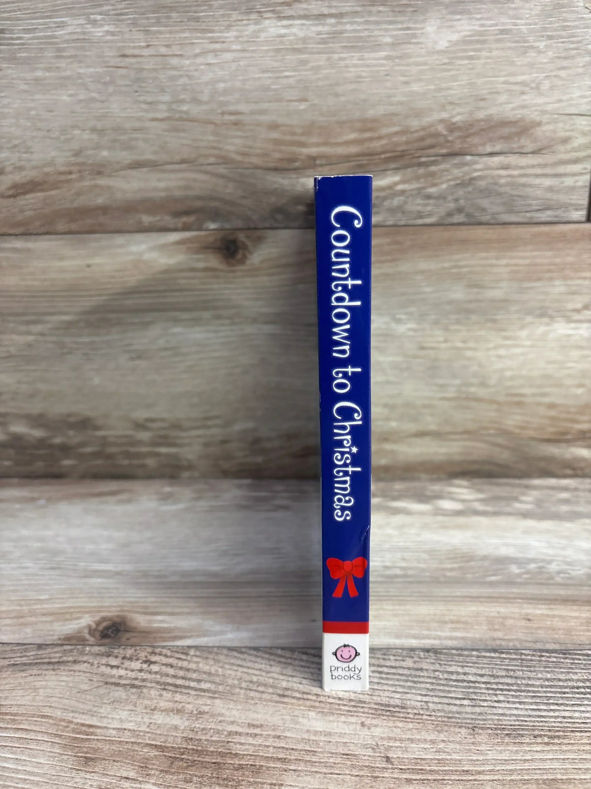 Countdown to Christmas kids book by Priddy Books, blue cover with red bow, on wood surface