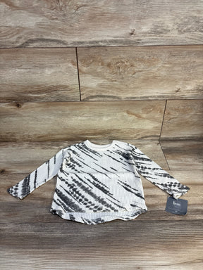 Flat lay of NEW Grayson Mini Waffle Knit Shirt in ivory showcasing black tie-dye pattern with hangtag on wood plank floor