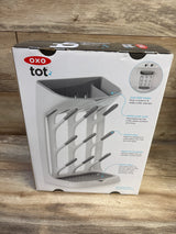Front view of NEW OXO Tot Space Saving Drying Rack box showcasing angled pegs and removable trays on a wood surface