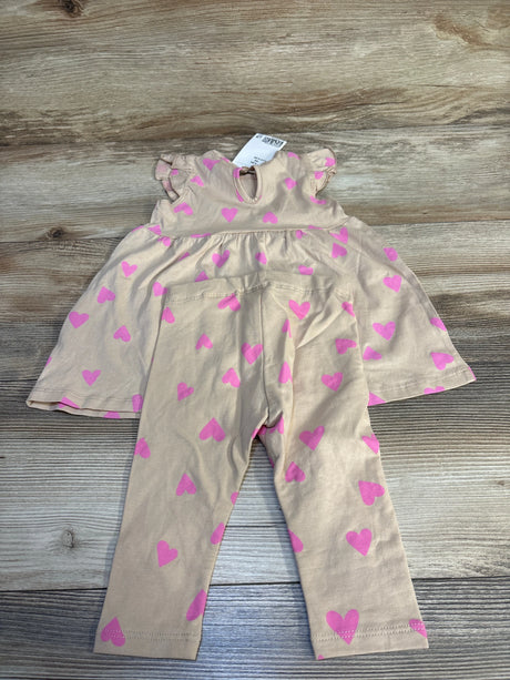 Beige toddler outfit with pink heart print, ruffle sleeves, and matching pants on wood floor