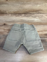 Back view of Cotton On Baby Jay Moto shorts in green, showing elastic waistband and two back patch pockets on wood backdrop