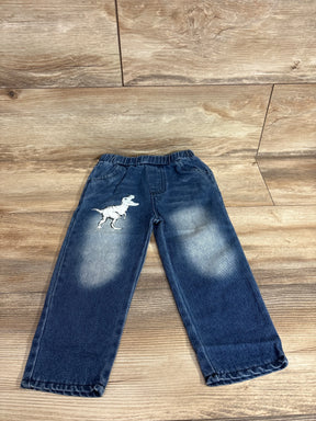 Front flat lay of toddler blue jeans with white T-Rex patch on left thigh, faded knees and elastic waist on wood floor