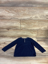 Flat lay of Cat & Jack navy waffle knit henley shirt, toddler size 3T, showcasing three-button placket, chest pocket and long sleeves on light wood background