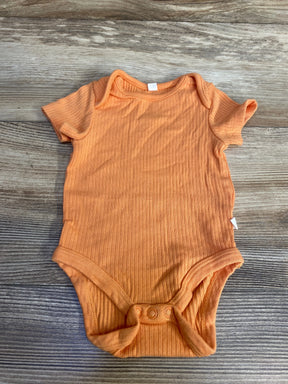 Top-down view of Mori ribbed orange newborn bodysuit 0-3M showing short sleeves, lap shoulder and three-snap crotch on wood surface
