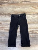 Top down view of black Cat and Jack toddler jeggings showing front button, belt loops and straight legs on a light wood background
